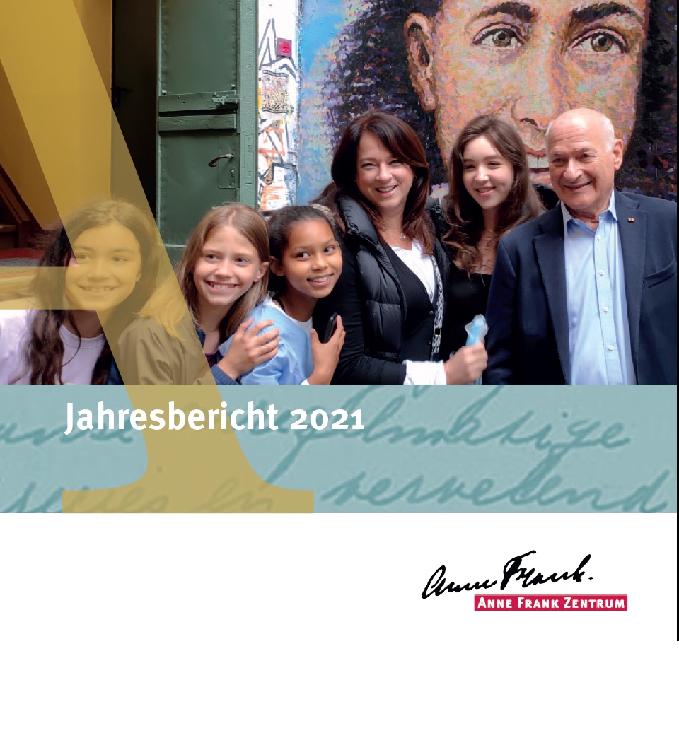Auf dem Bild sieht man Menschen unterschiedlichen Alters, sie stehen vor einem Bild von Anne Frank. Vor der gruppe steht Jahresbericht 2021