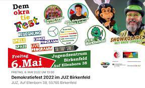 Das Bild ist eine Ankündigung für das Demokratiefest 2022. Es ist bunt und drei beteiligte Künstler sind darauf abgebildet.