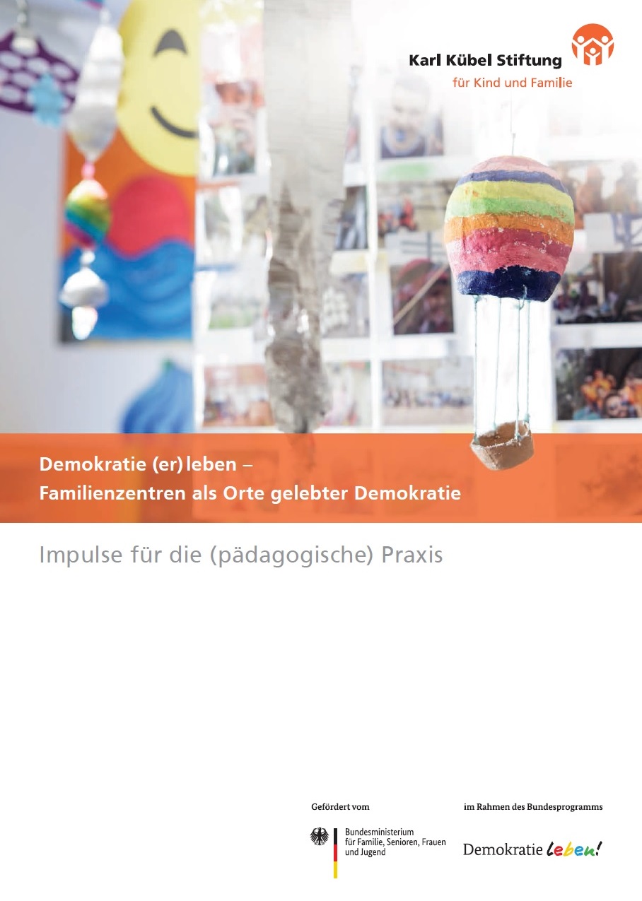 Auf dem Bild steht Demokratie erleben - Familienzentren als Orte gelebter Demokratie. Im Hintergrund sieht man Fotos a einer Wand hängen, davor ein selbstgebastelter kleiner Ballon.