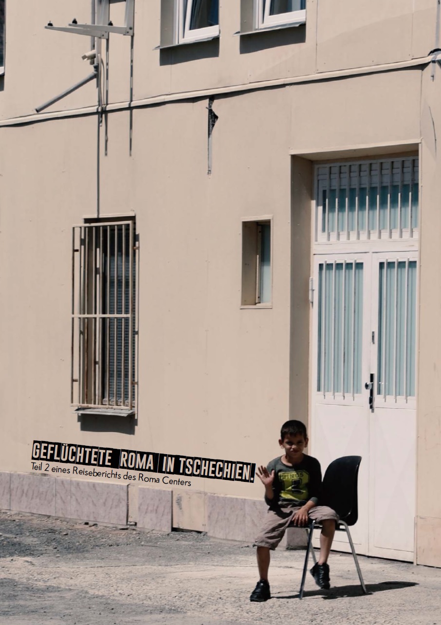 Auf dem Bild sitzt ein Junge draußen vor einem Haus, und grüßt mit seiner Hand in die Kamera. Vor einem Fenster sind Gitter angebracht. Neben dem Jungen steht Geflüchtete Roma in Tschechien. Teil 2 eines Reiseberichts des Roma Centers